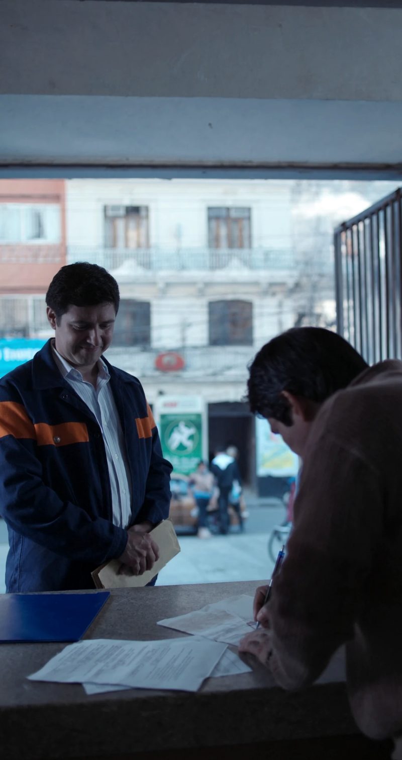 Imagen ilustrativa: un cliente firma la escritura sobre el mostrador de su local mientras el mensajero de la notaría espera con el sobre